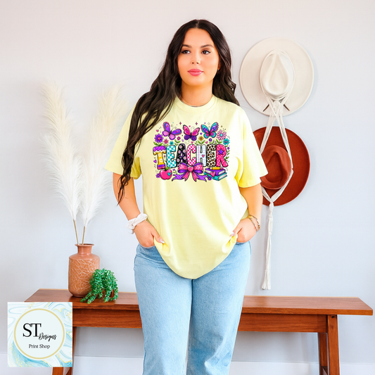 Colorful teacher graphic crewneck sweatshirt by ST Designs Store, featuring vibrant educational-themed illustrations on a sand-colored fabric.