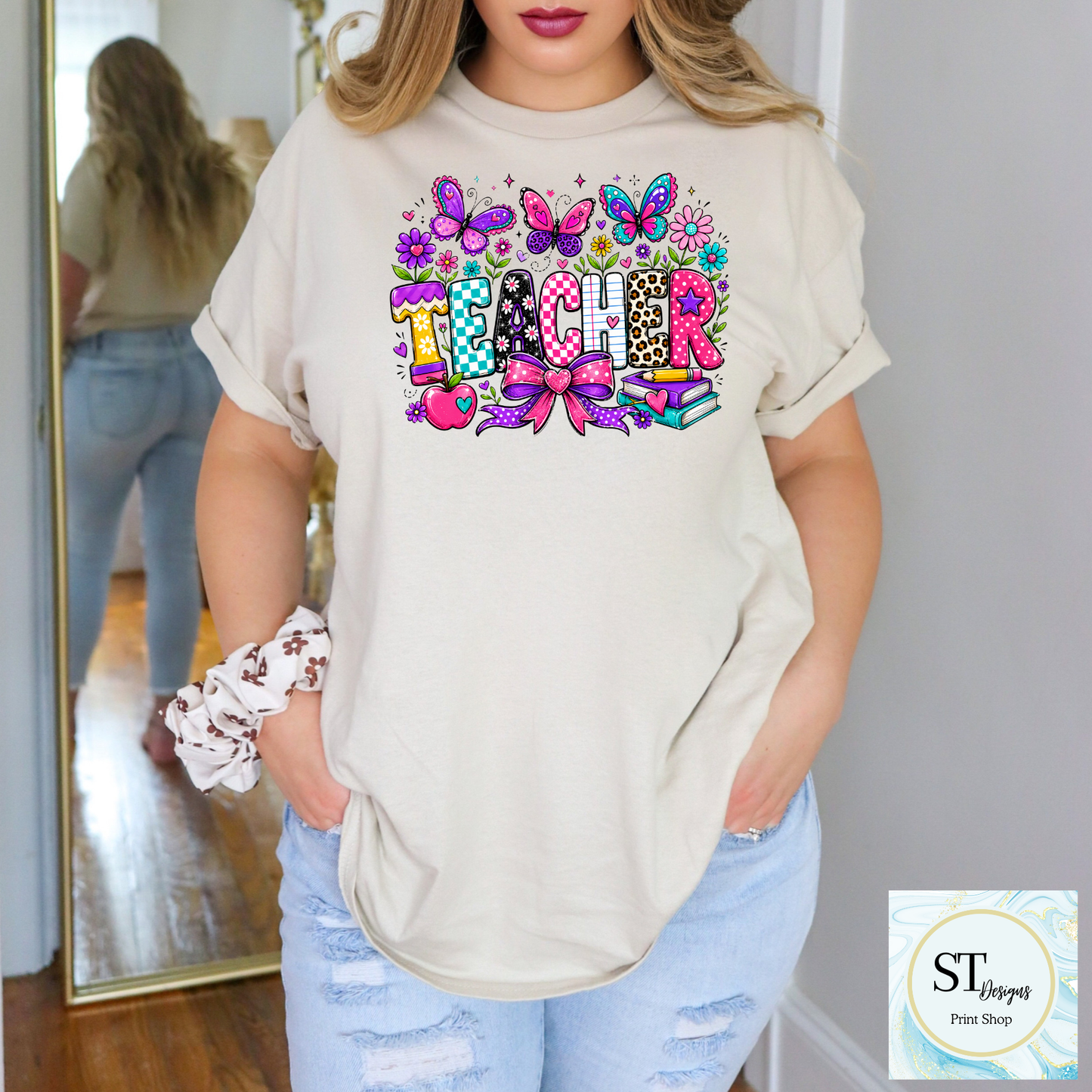 Colorful teacher graphic crewneck sweatshirt from ST Designs Store with vibrant, playful design on a sand-colored fabric.