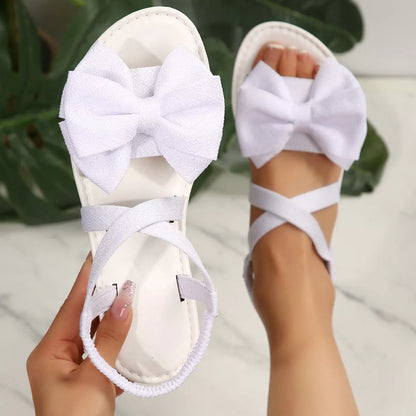 Black Bow Embellished Flat Sandals by Trendsi with decorative bows and comfortable flat sole, stylish for casual wear.