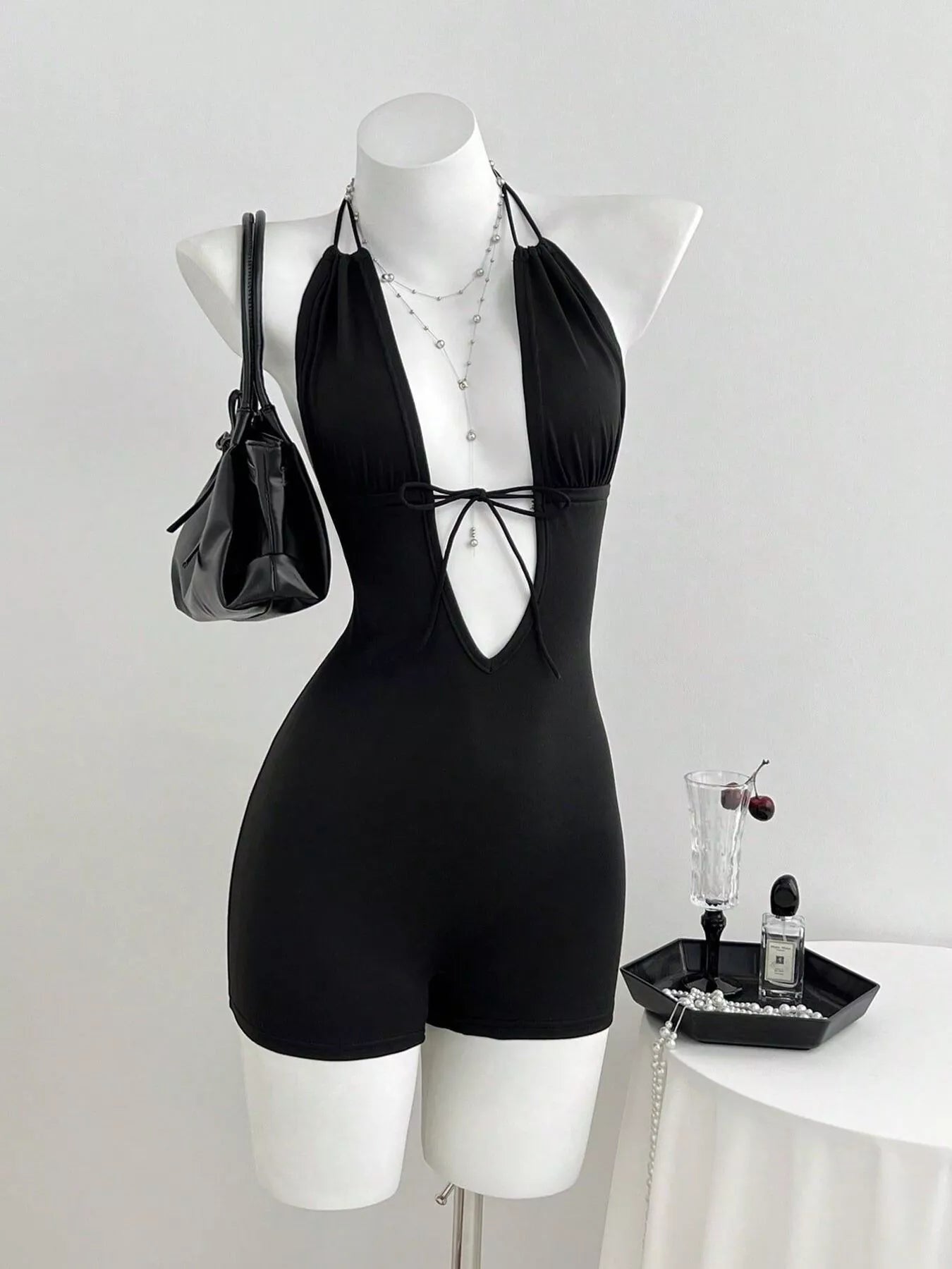 Black tied front halter neck romper by Trendsi, featuring a stylish halter design and fitted silhouette for a trendy summer look.