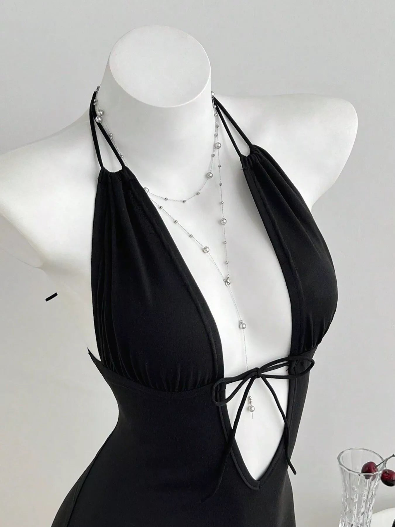 Black tied front halter neck romper by Trendsi, featuring a stylish design with a fitted waist and sleeveless silhouette.