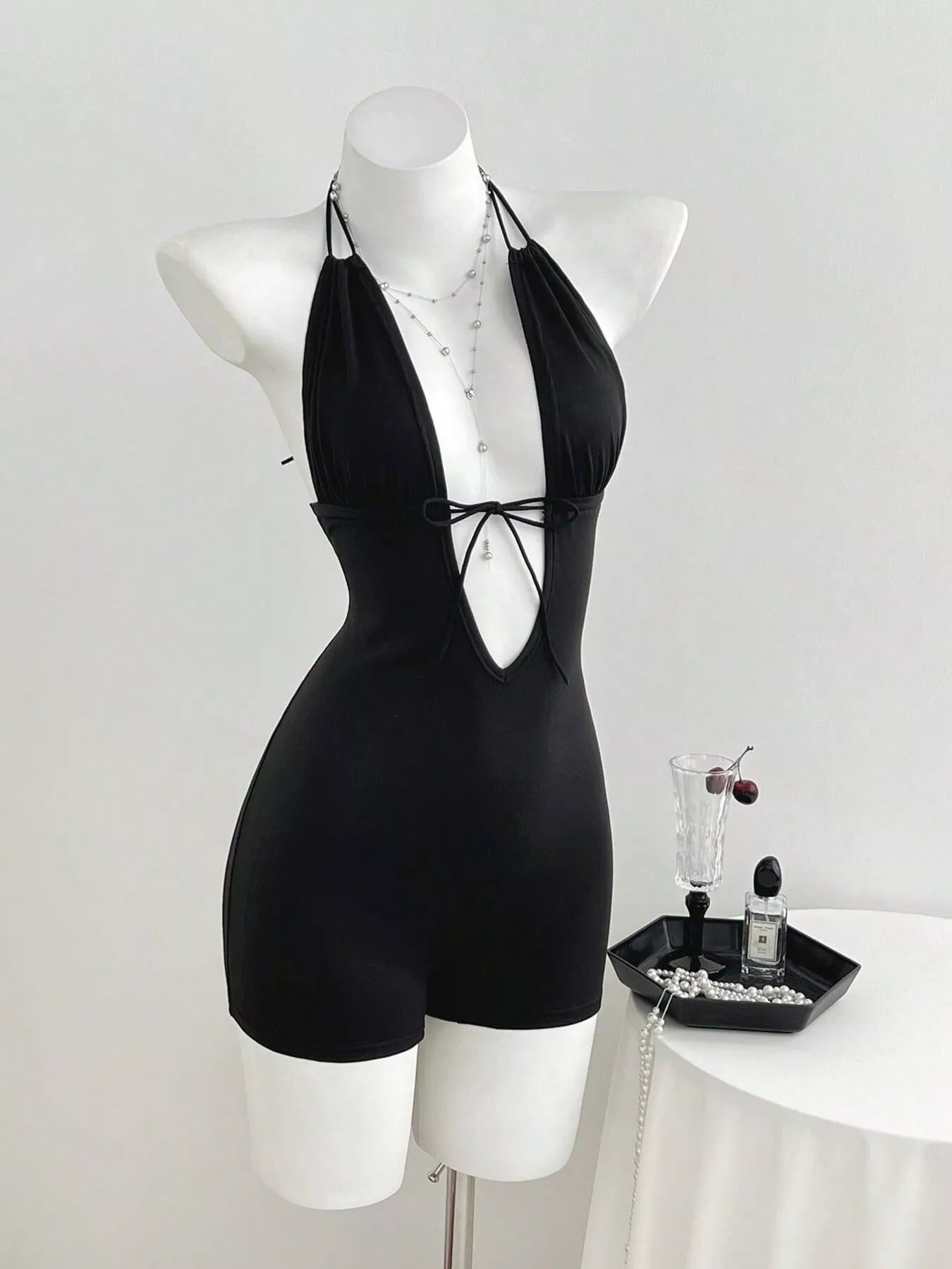 Black tied front halter neck romper by Trendsi, featuring a sleeveless design and stylish front tie detail.