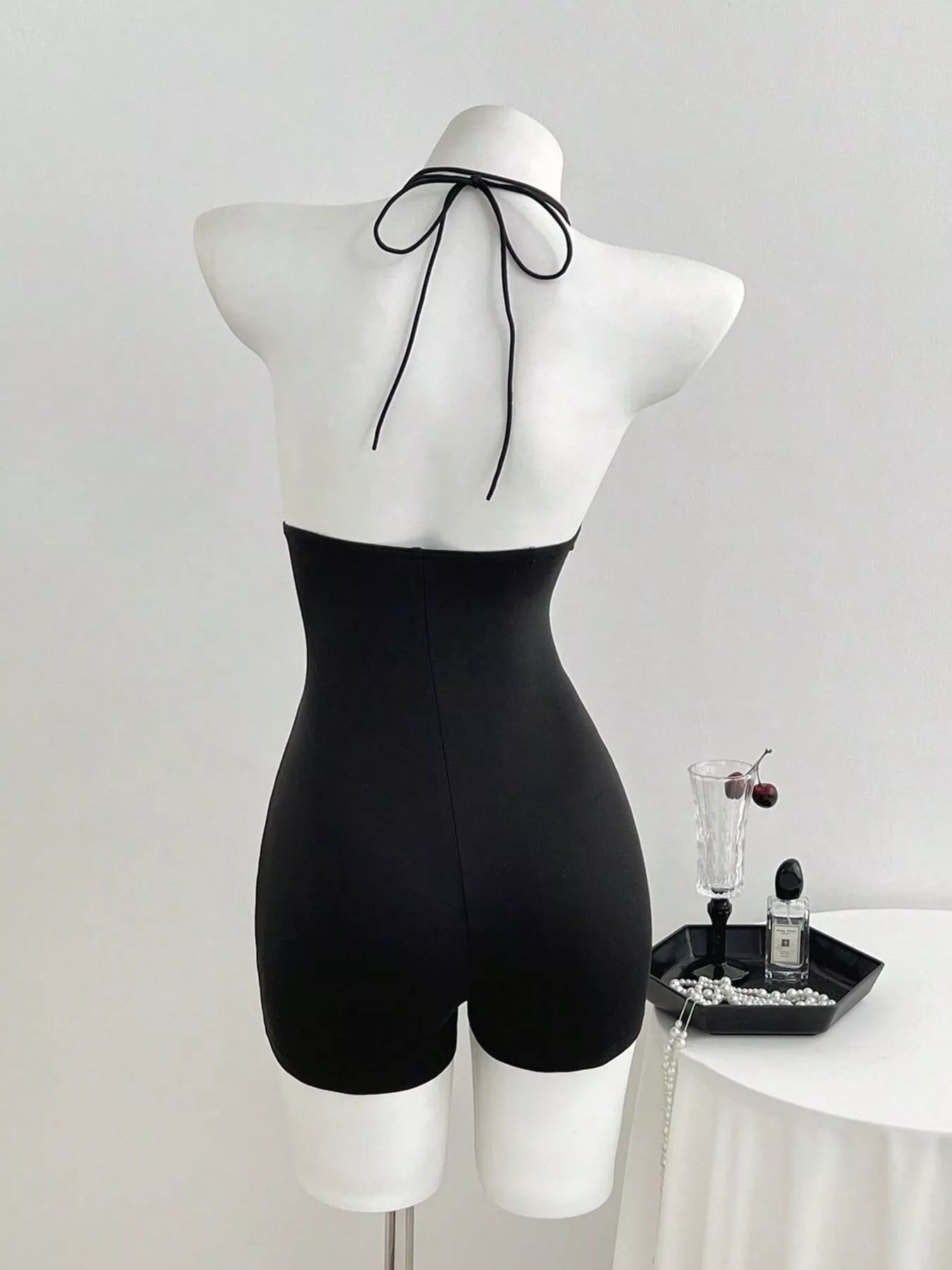 Black tied front halter neck romper by Trendsi, featuring a stylish halter design and a relaxed fit.