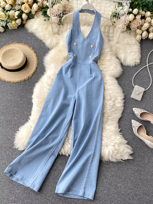 Halter neck wide-leg denim jumpsuit from Trendsi, featuring a fitted bodice and flowing pant legs, styled for casual wear.