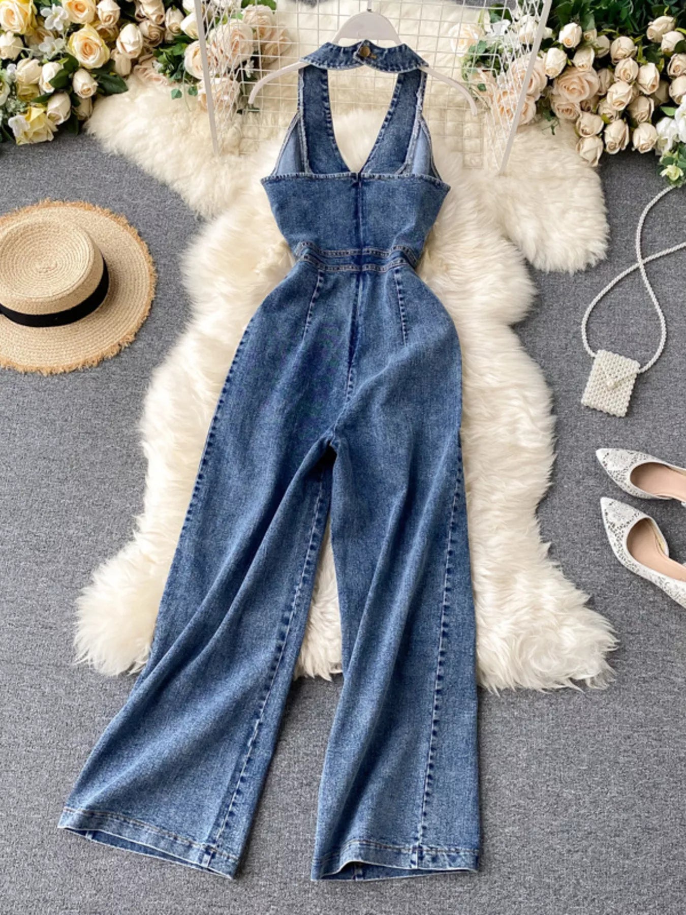 Halter neck wide-leg denim jumpsuit by Trendsi, featuring a fitted bodice and flowing pant legs, casual and stylish for warm weather.