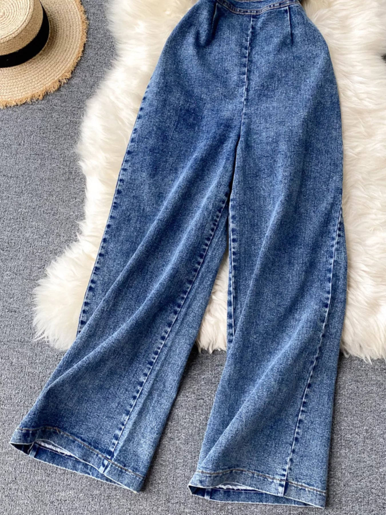 Halter neck wide leg denim jumpsuit by Trendsi featuring a fitted top and flowing wide-leg pants, made from classic blue denim fabric.