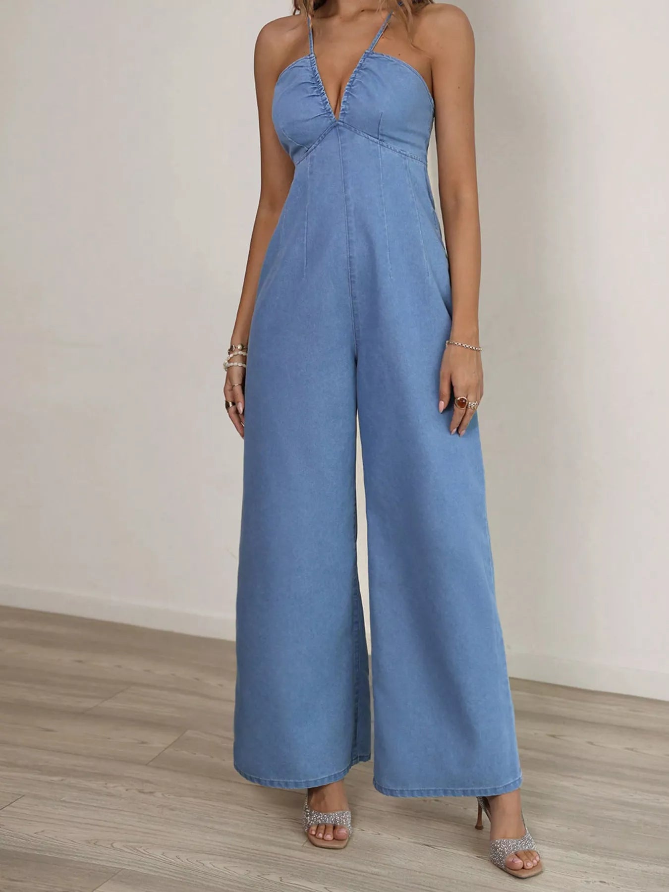 Blue denim jumpsuit with spaghetti straps and wide leg design, stylish and casual, from Trendsi.