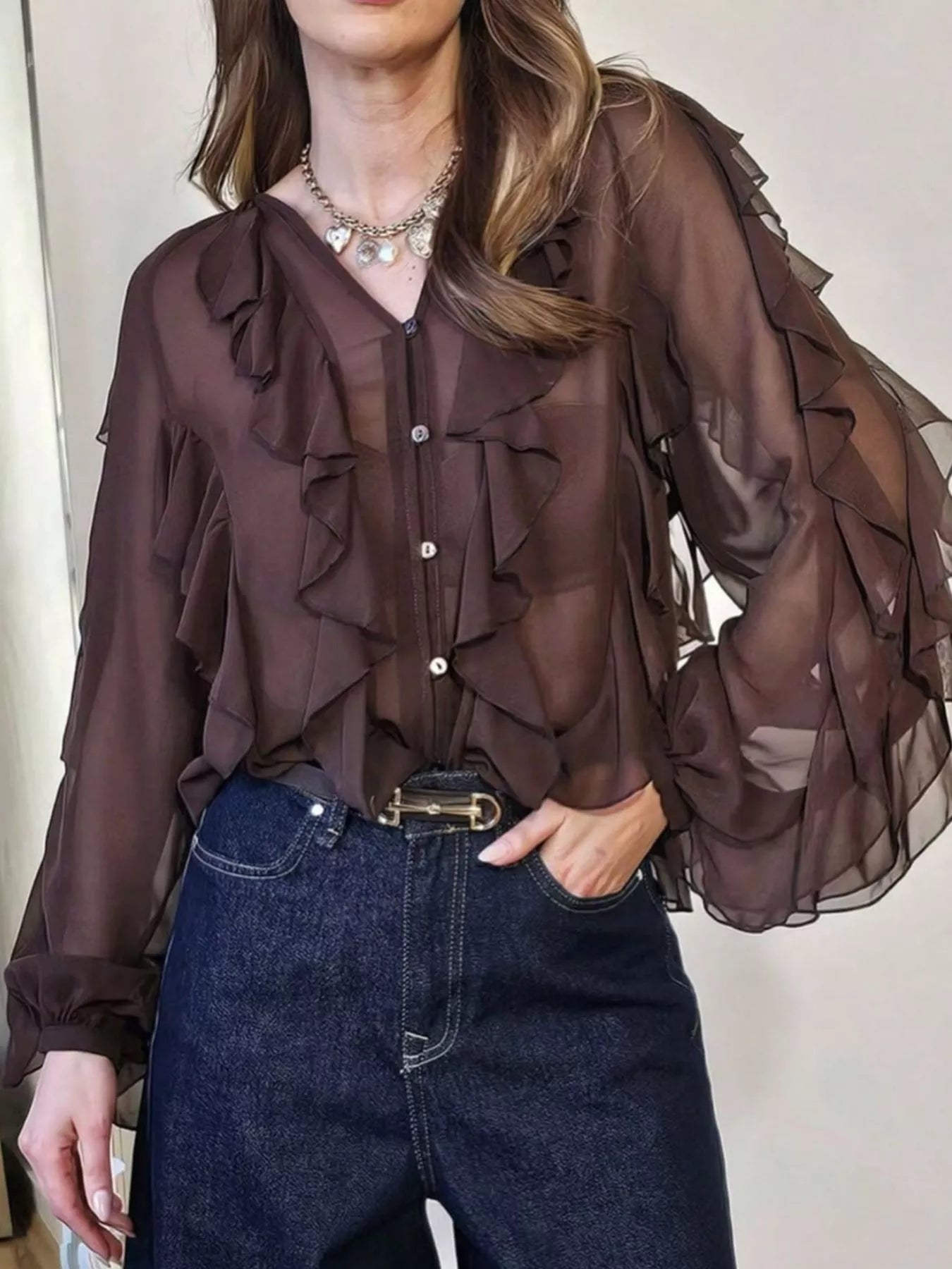 Ruffled sheer long sleeve blouse by Trendsi, featuring delicate fabric, ruffle details, and a stylish, feminine design.