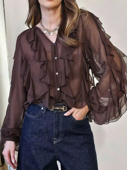 Ruffled sheer long sleeve blouse by Trendsi, featuring delicate fabric, ruffle details, and a stylish, feminine design.