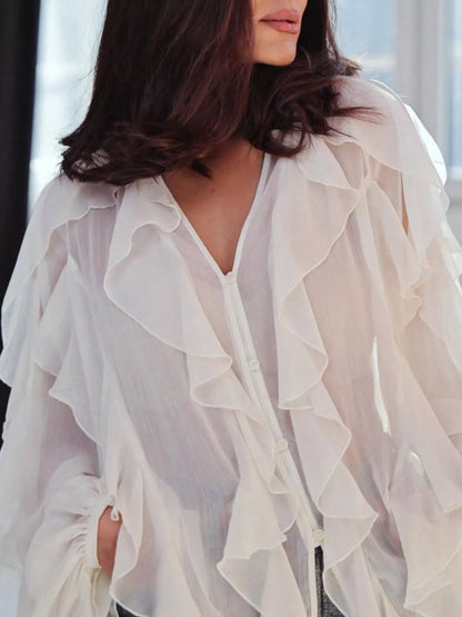 Sheer long sleeve blouse with ruffled details from Trendsi, featuring a delicate, feminine design and elegant ruffle accents.