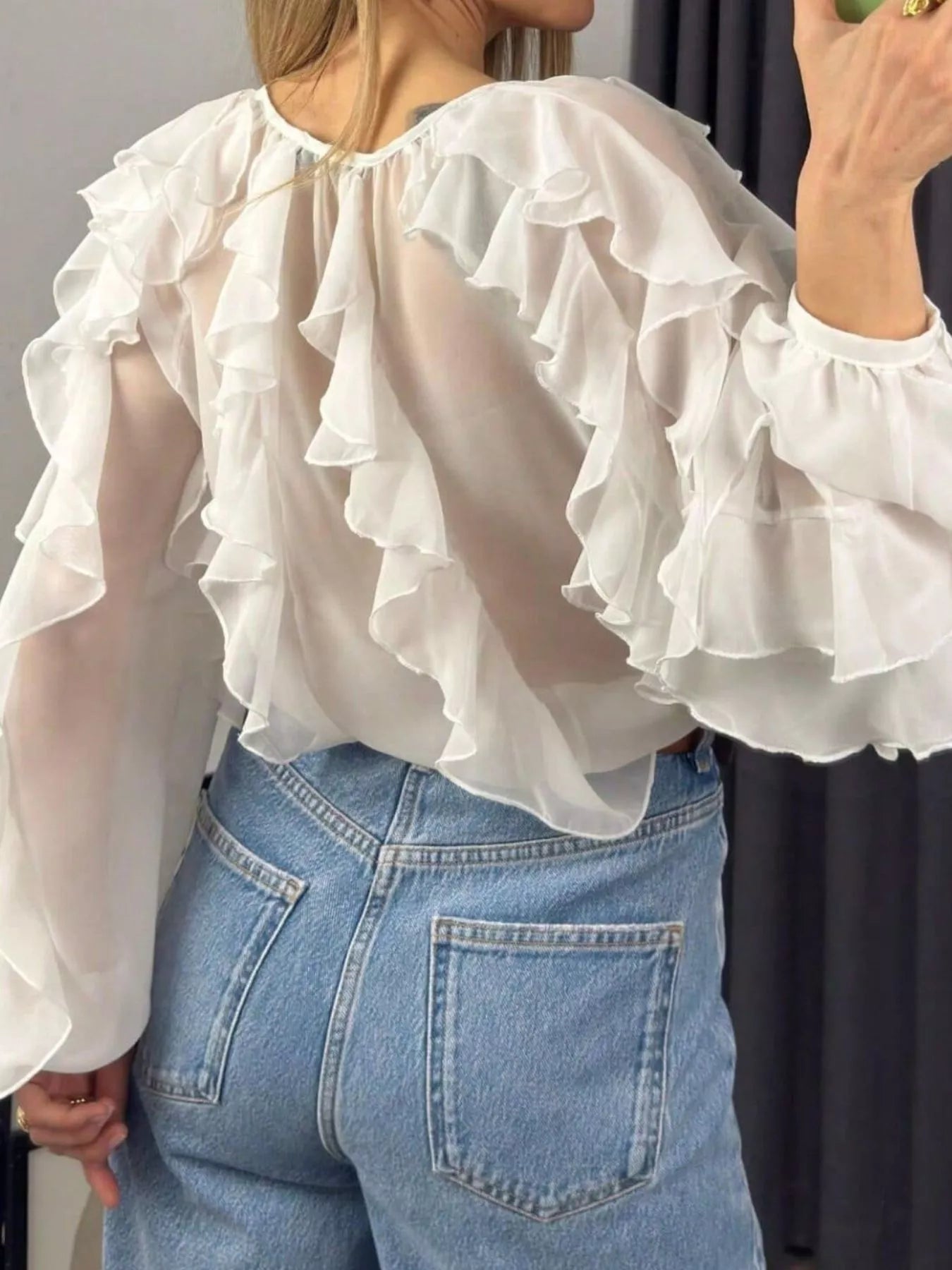 Sheer long sleeve blouse with ruffled details from Trendsi, featuring delicate fabric and feminine design.
