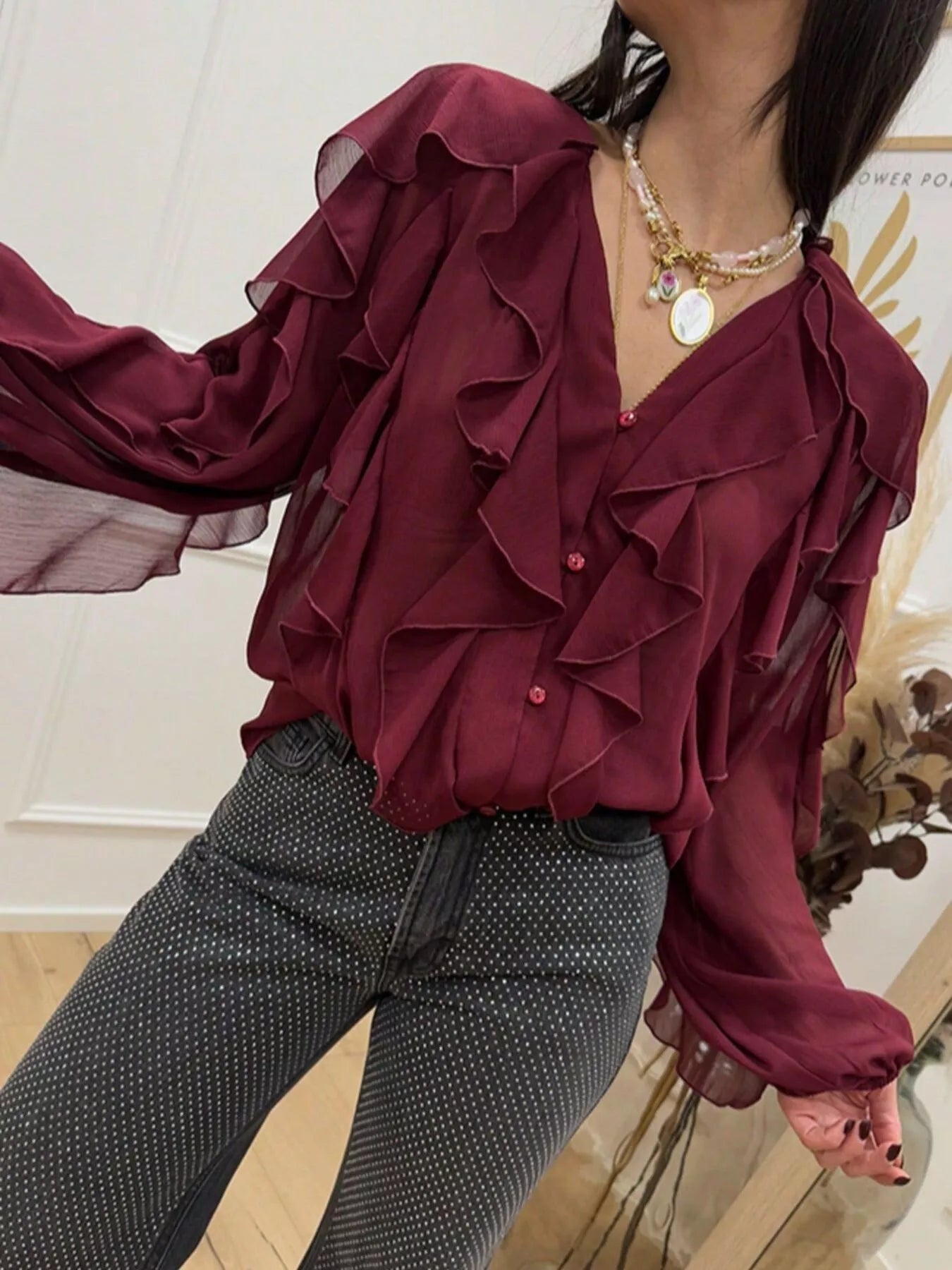 Ruffled sheer long sleeve blouse by Trendsi featuring delicate ruffles and lightweight, transparent fabric for a feminine look.