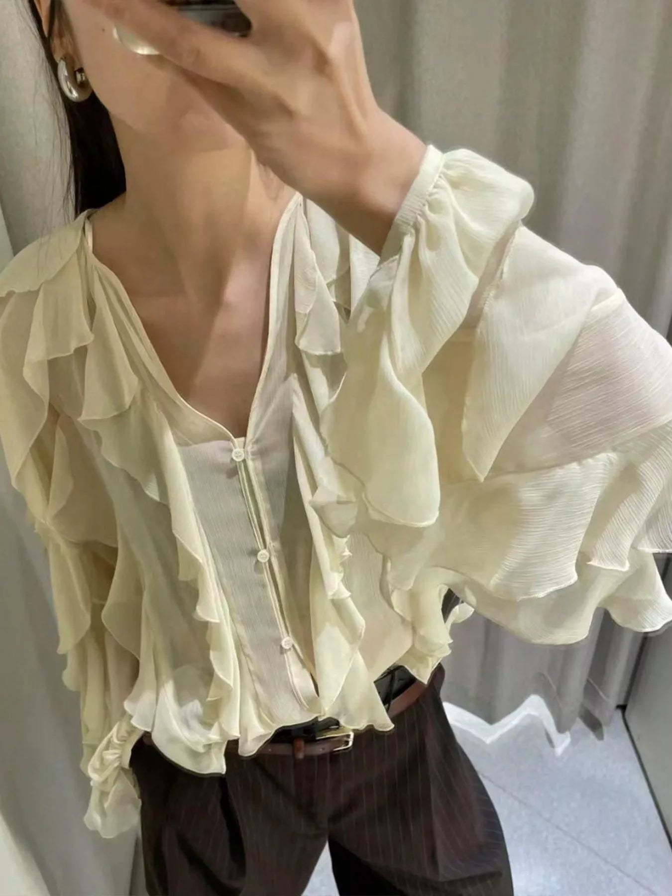 Brown ruffled sheer long sleeve blouse by Trendsi featuring delicate ruffle details and a lightweight, transparent fabric.