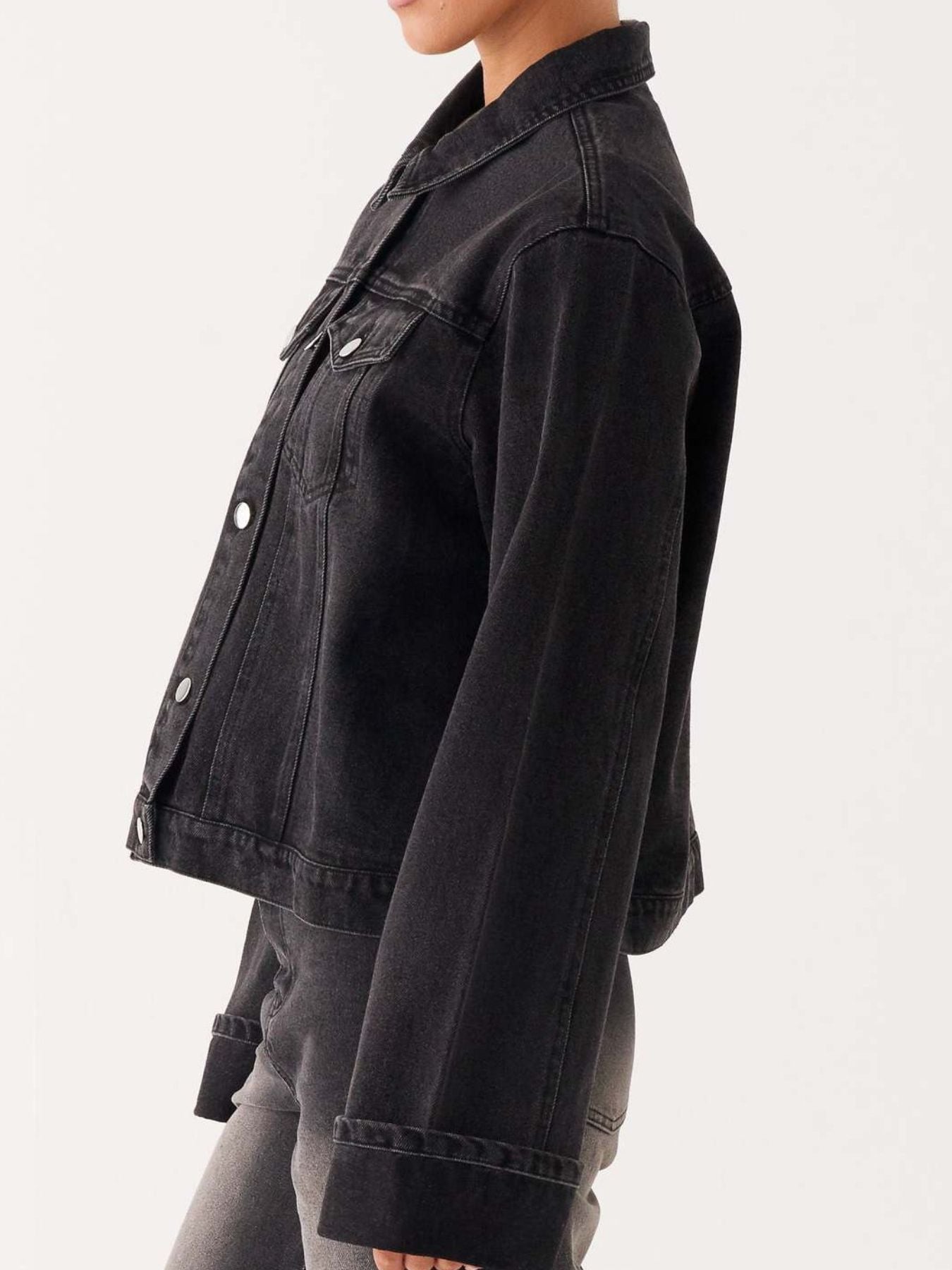 Dark blue oversized denim jacket with button-down front and cropped style, featuring long sleeves and classic denim texture.