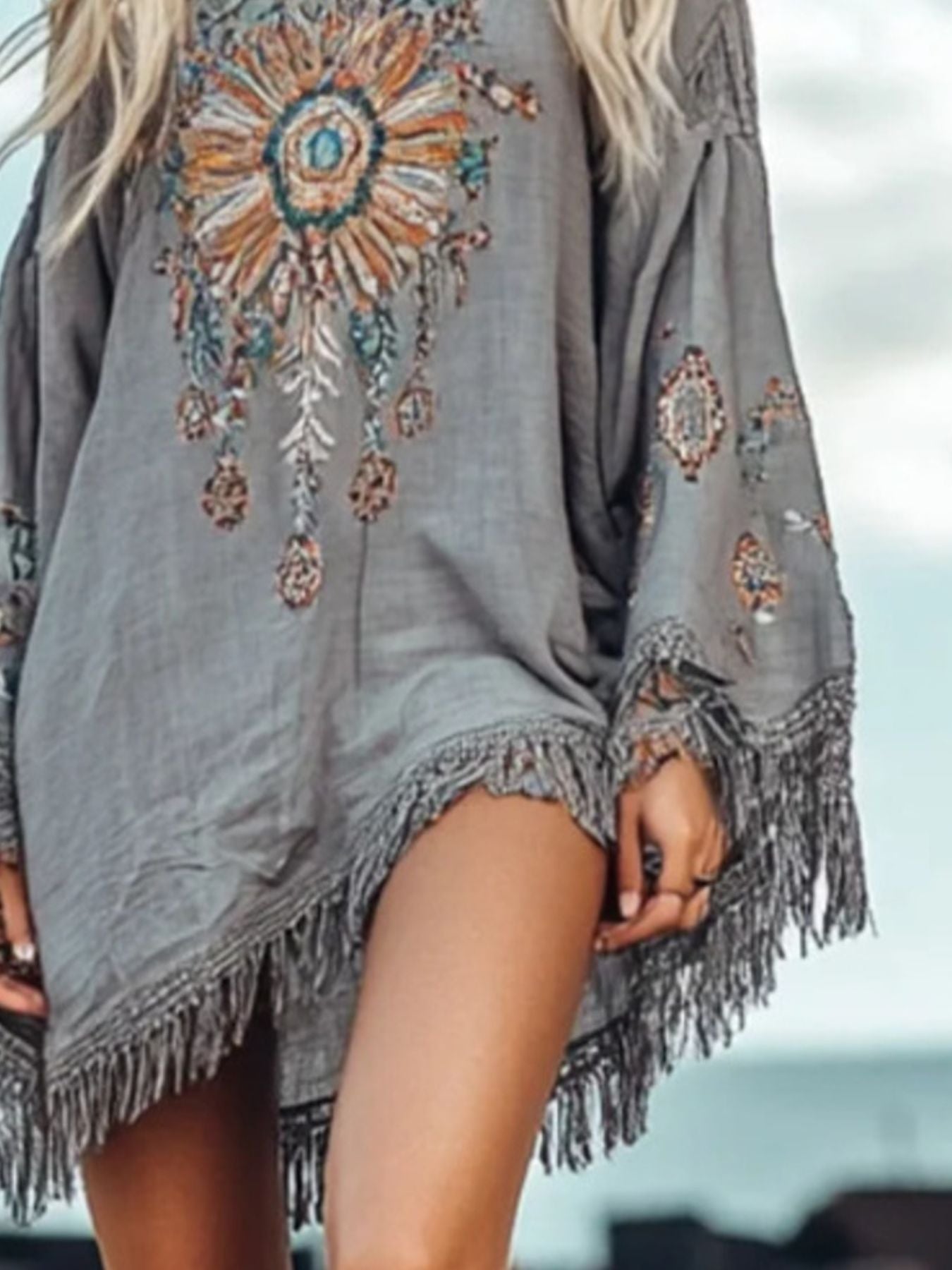 Long sleeve mini dress with fringe hem from Trendsi, featuring a stylish and trendy design perfect for casual or festive occasions.