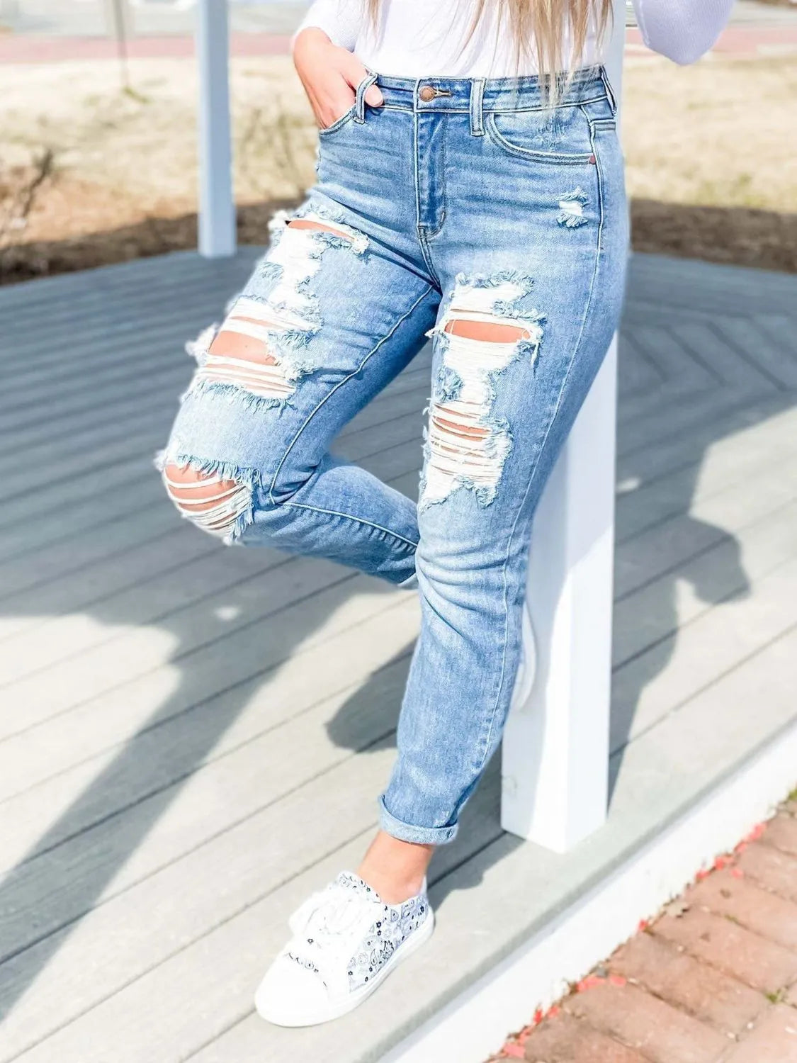 Light blue distressed skinny jeans by Trendsi, showing a fitted denim style with intentional rips and ruffled hem detail.
