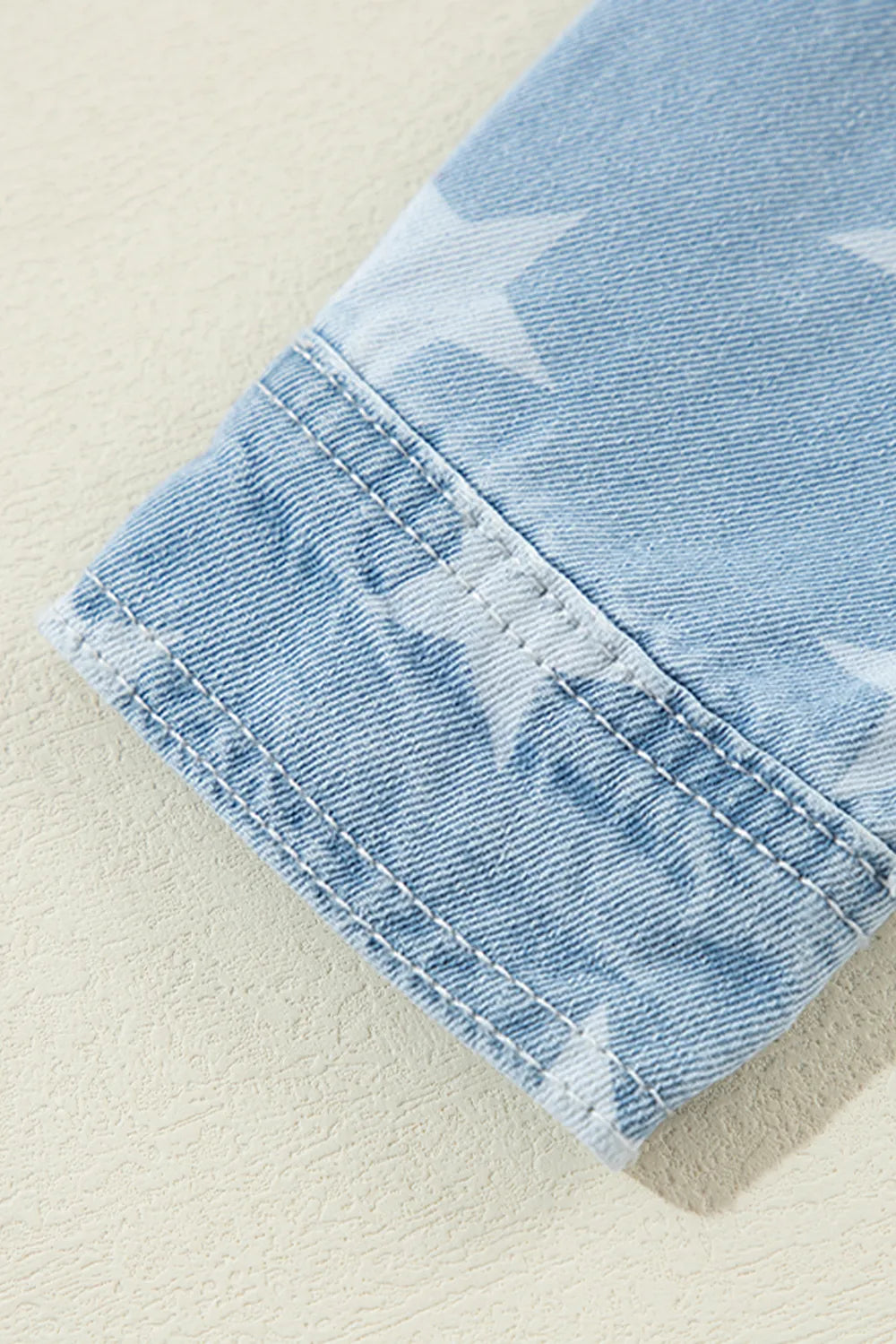 Raw hem star-embellished denim top with a collared neckline, featuring a trendy raw hem design and classic denim texture.