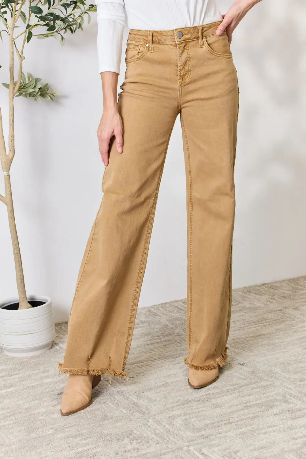 Risen full size fringe hem wide leg jeans in denim, featuring a relaxed fit and stylish fringe details at the hem.