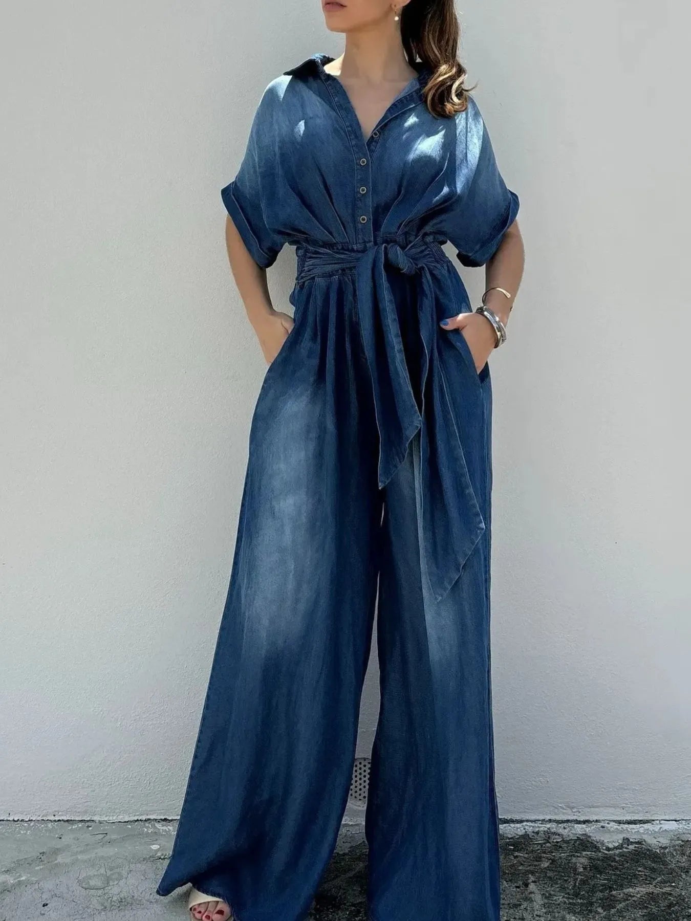 Vintage blue denim jumpsuit with button front and wide-leg design, by Trendsi, showcasing casual, comfortable style.