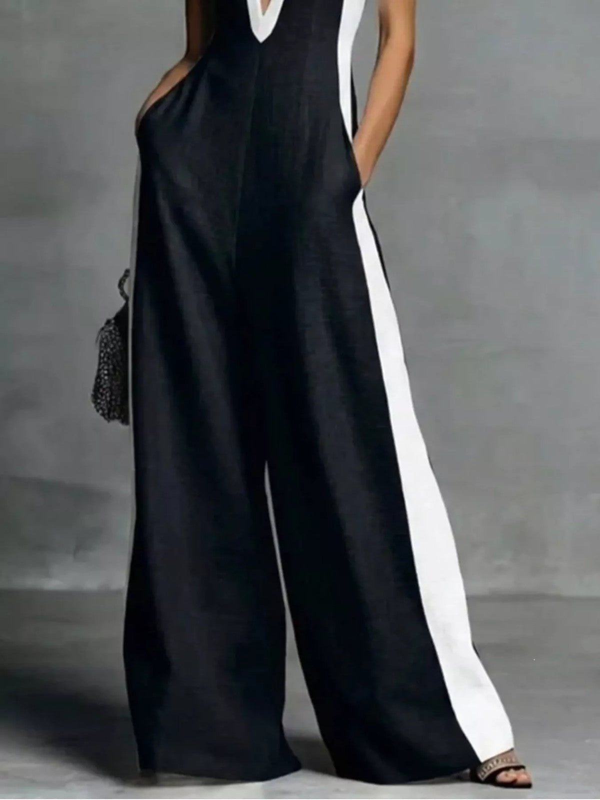 Deep V-neck wide-leg jumpsuit with contrast trim, featuring flowy fabric and stylish design, perfect for casual or dressy occasions.